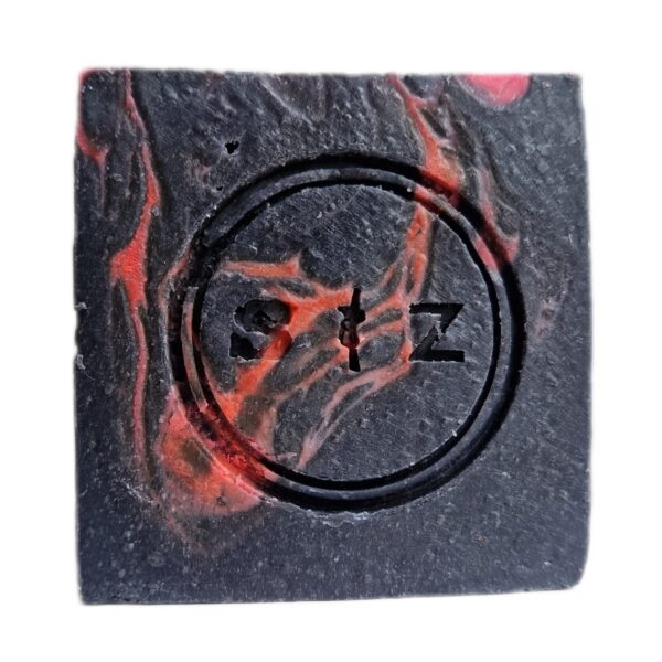 Vierkante zeepbar van voren gezien, zwart en neonroze gemarmerd van kleur. In het midden van de zeep is een rond logo gestempeld met de tekst 's & z'.