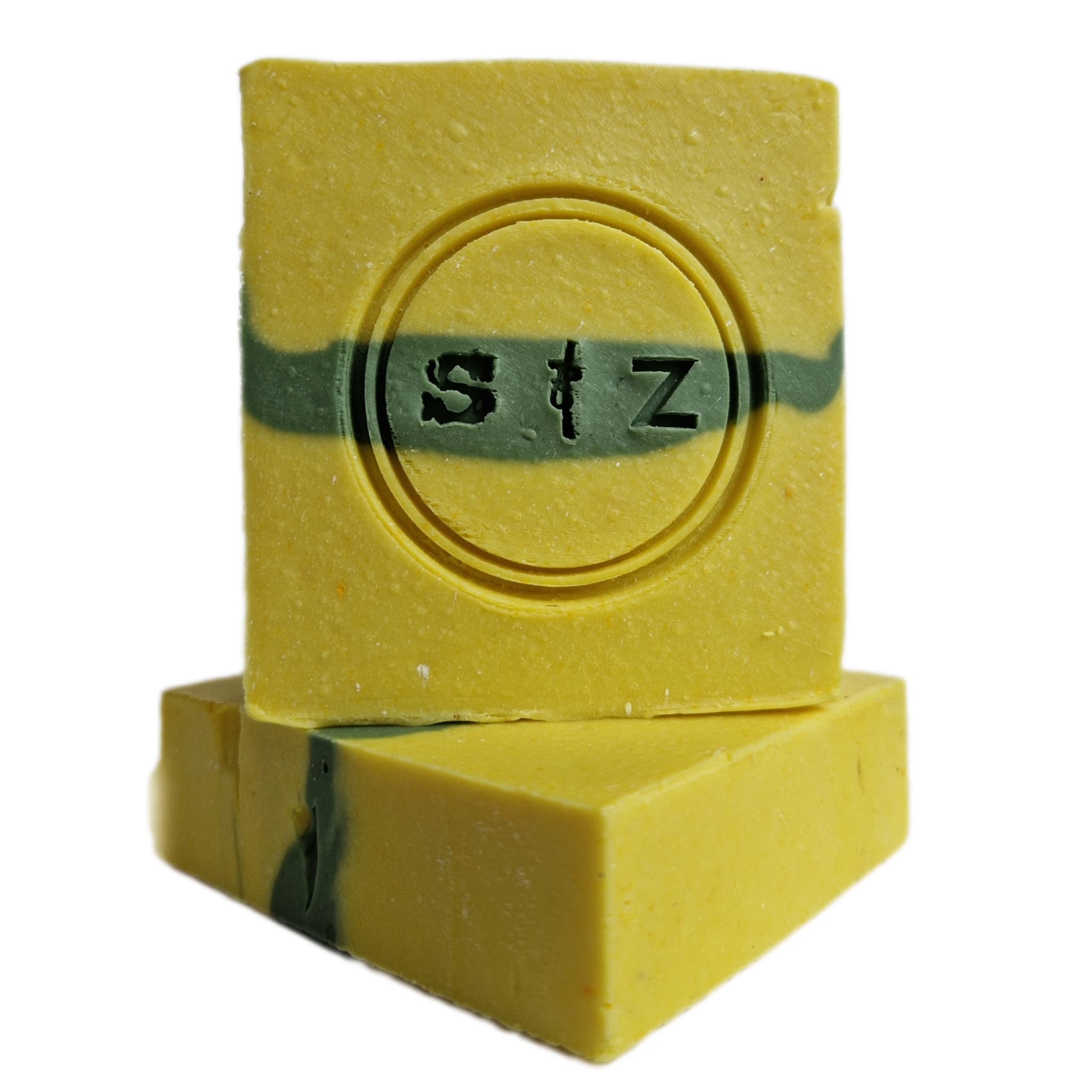 Twee vierkante zeepbars, die op elkaar gestapeld staan. De bovenste zeepbar zie je recht van voren, de onderste zeepbar ligt en is schuin gedraaid. Geel van kleur met een groene streep in het midden. In het midden van de zeep is een rond logo gestempeld met de tekst 's & z'.